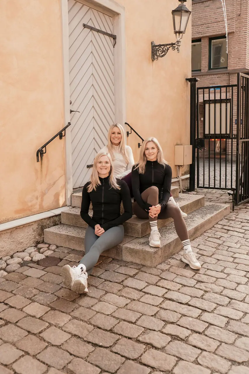 Three Sweden female fitness trainers sitting on a small set of stairs